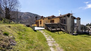 A stone building with a yellow facade, a stone staircase, and a clear sky. - Room 'Camera B' – Prato Fiorito with Mountain View and Shared Pool (Bagni di Lucca)