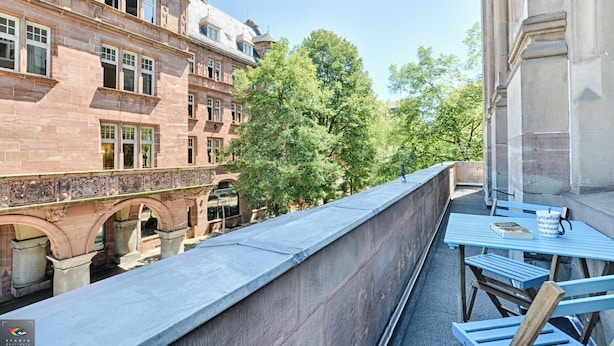 A balcony with a view of a historic building, a stone bridge, and lush trees. - City Suite German Chic The Imperial Balcony (Metz)