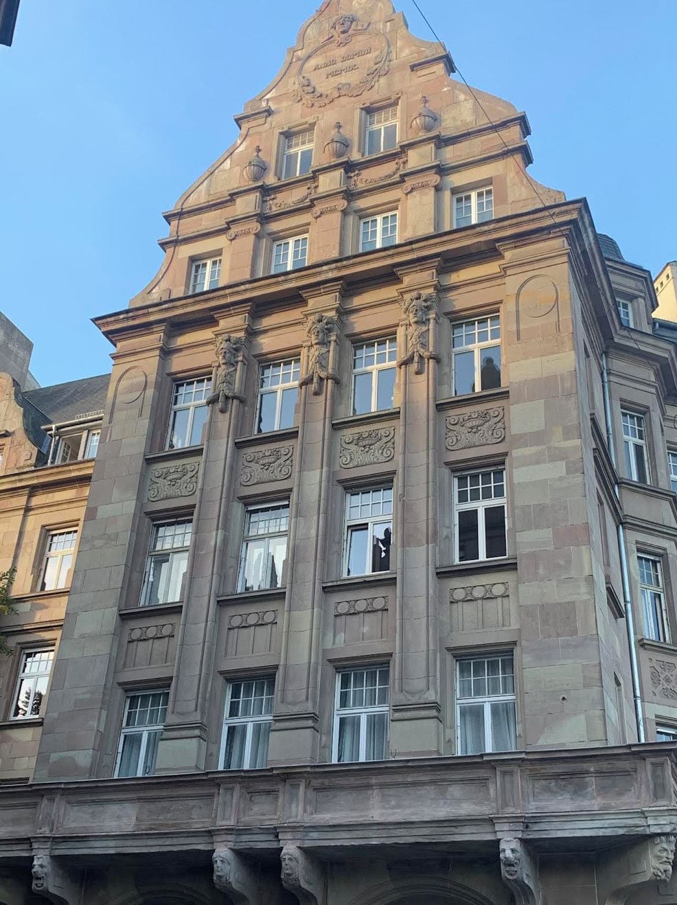 A multi-story building with classical architectural features, including ornate carvings and a prominent triangular pediment.