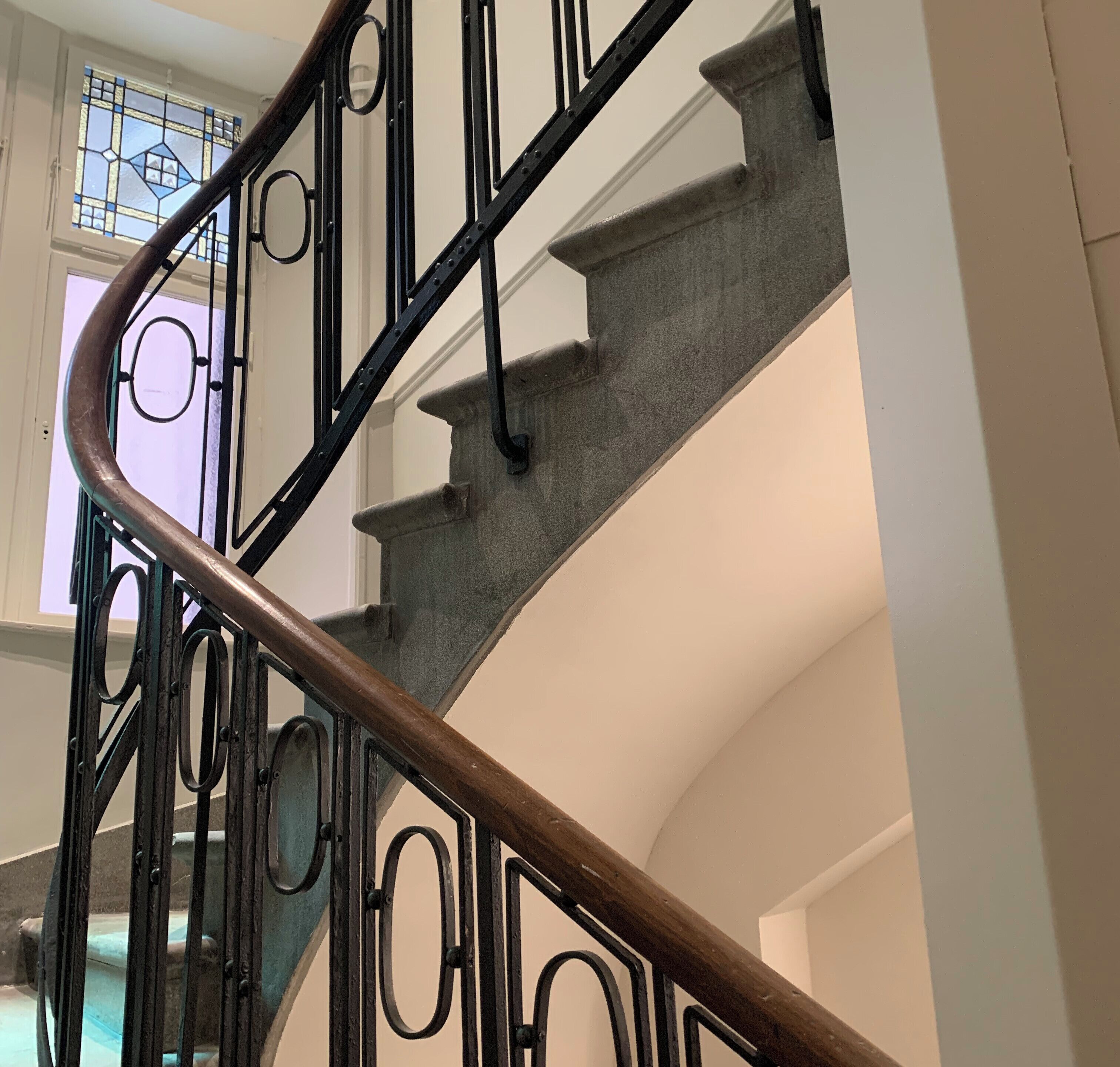 Un escalier en colimaçon avec des rampes en métal et une main courante en bois.