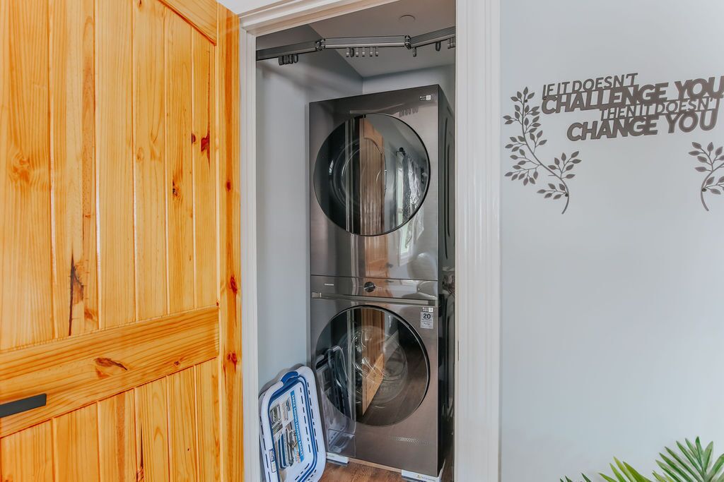 Ein kleiner Waschraum mit zwei Edelstahl-Waschmaschinen, einem Holzschrank und einem motivierenden Spruch an der Wand.