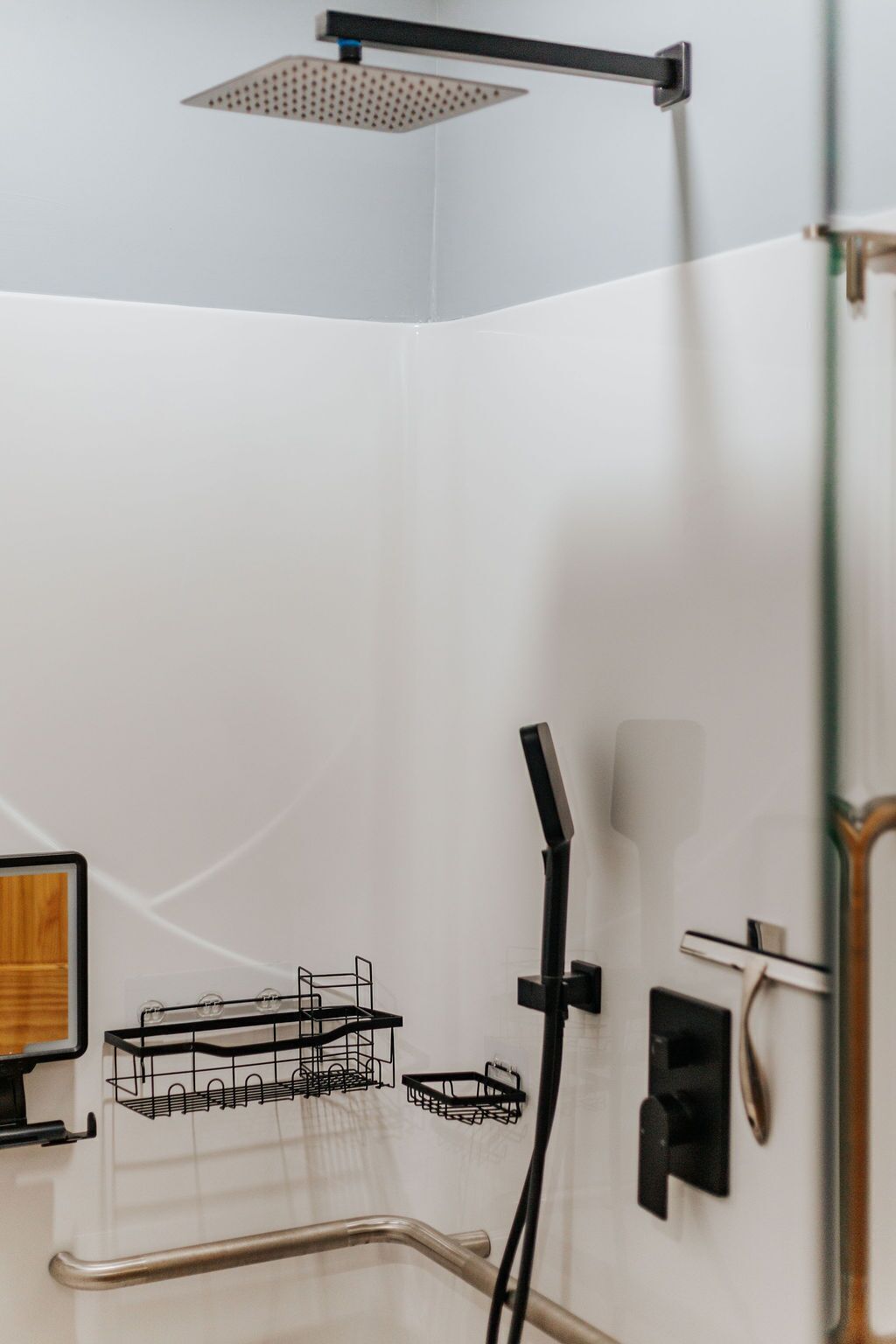 A modern bathroom with a shower, a towel rack, and a glass shower door.