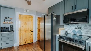 Una cocina moderna con gabinetes grises, un refrigerador de acero inoxidable, horno empotrado y microondas.