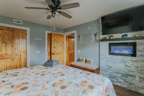 Un dormitorio con cama, armario de madera, televisor y chimenea.