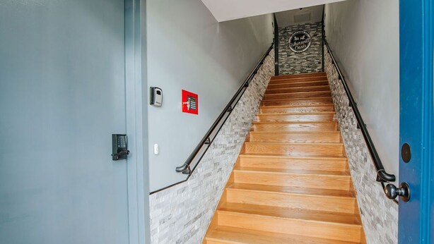 Un escalier en bois, un mur d’accent en pierre, une porte bleue et un détecteur d’incendie sur le mur.