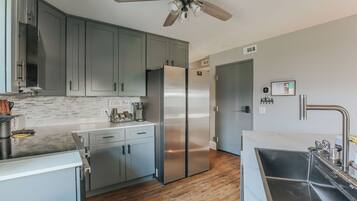 Une cuisine moderne avec des meubles gris, des appareils en acier inoxydable et un plancher en bois.