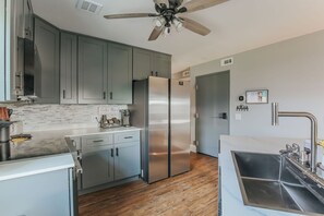 Una cocina moderna con armarios grises, electrodomésticos de acero inoxidable y piso de madera.