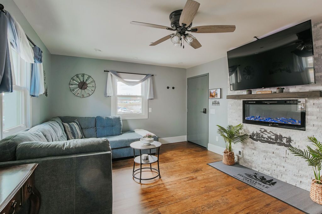 A living room with a sofa, a coffee table, a TV mounted on the wall, and a fireplace.