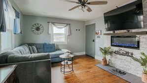 Un salon comprenant un canapé, une table basse, un téléviseur fixé au mur et une cheminée.
