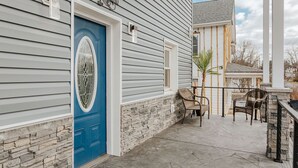 Une maison avec une porte bleue, un mur en pierre et une terrasse avec des chaises.