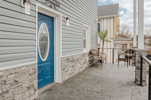 Ein Haus mit blauer Tür, Steinwand und einer Terrasse mit Sitzgelegenheiten.