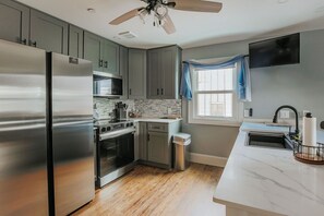 A modern kitchen with stainless steel appliances, a wooden floor, and a ceiling fan. - Country Oasis: NEW Fishersville Apartment (Fishersville)