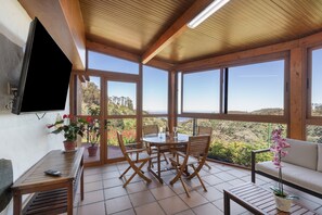 Une pièce avec un cadre en bois, comprenant une télévision, une table avec des chaises, un canapé et une plante en pot.
