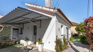 A single-story house with a covered porch, a chimney, and a small garden.