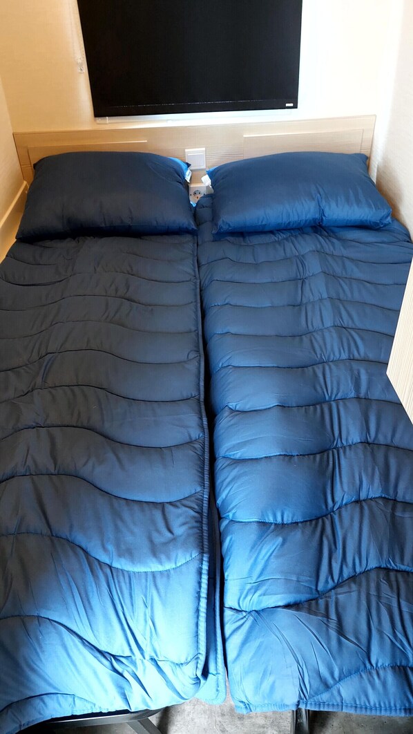 A bed with a blue quilt, a bedside table with a lamp, and a window above the bed. - Kamperland Beach Resort - 765 (Kamperland)
