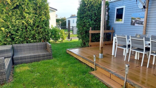 Eine Terrasse mit Gartenmöbeln, einer Holzpergola und einem kleinen Gartenhaus.