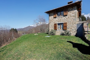 Ein Haus aus Stein mit einem geneigten Dach, Holzhörnern und einem kleinen Garten.