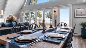 A dining area with a wooden table set for six, large windows, and a view of the beach. - Moonlight Bay Retreat, Waterfront home near Cana Island. (Baileys Harbor)