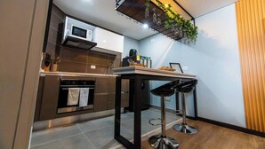 Une cuisine compacte équipée d’un four à micro-ondes, d’un four et de tabourets de bar.