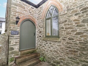 A stone cottage with a green door and a window with a white curtain. - Flagstaff Cottage (Saltash)