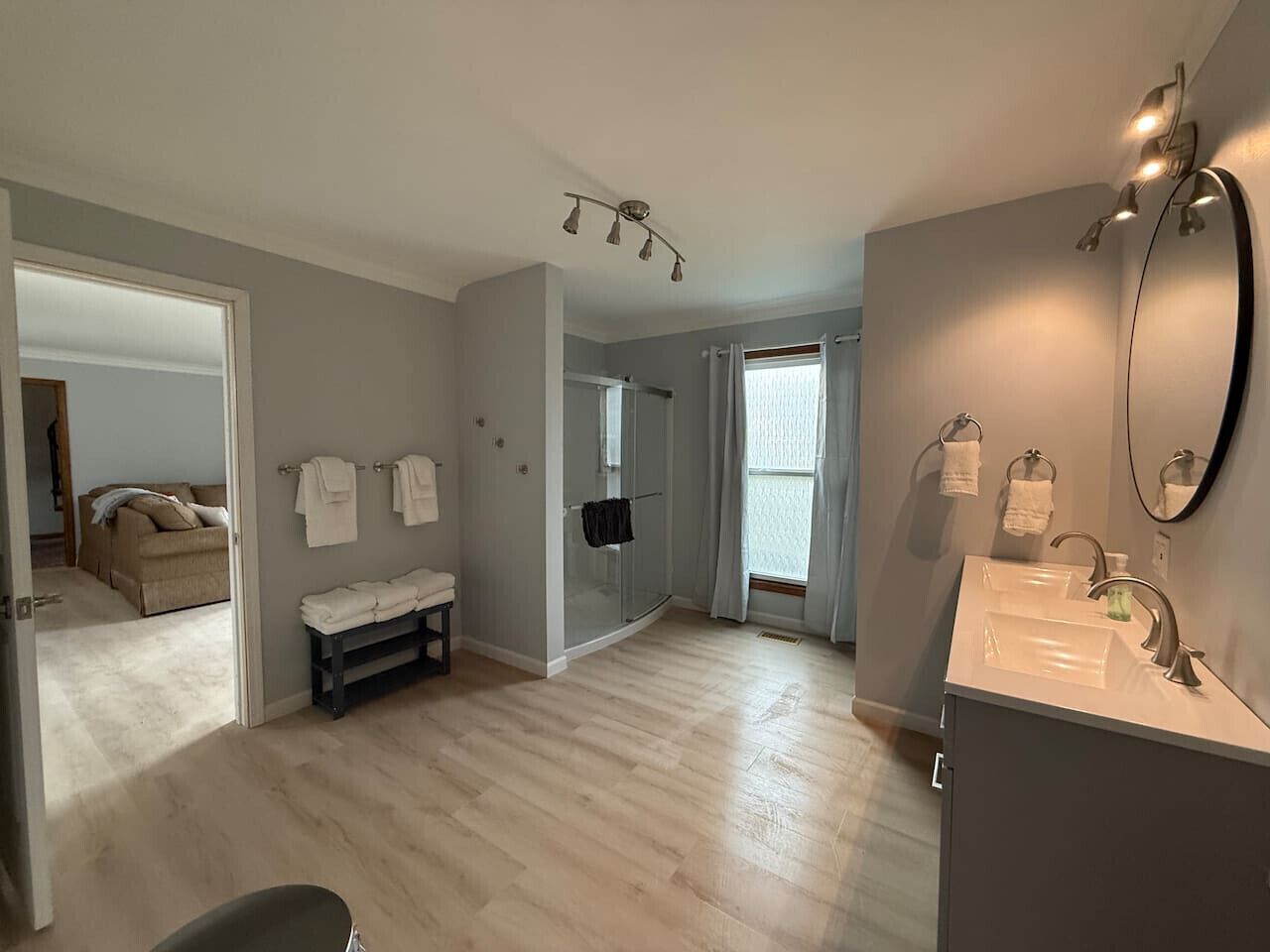 Une salle de bain spacieuse avec une douche, un meuble-lavabo avec un miroir et un banc.