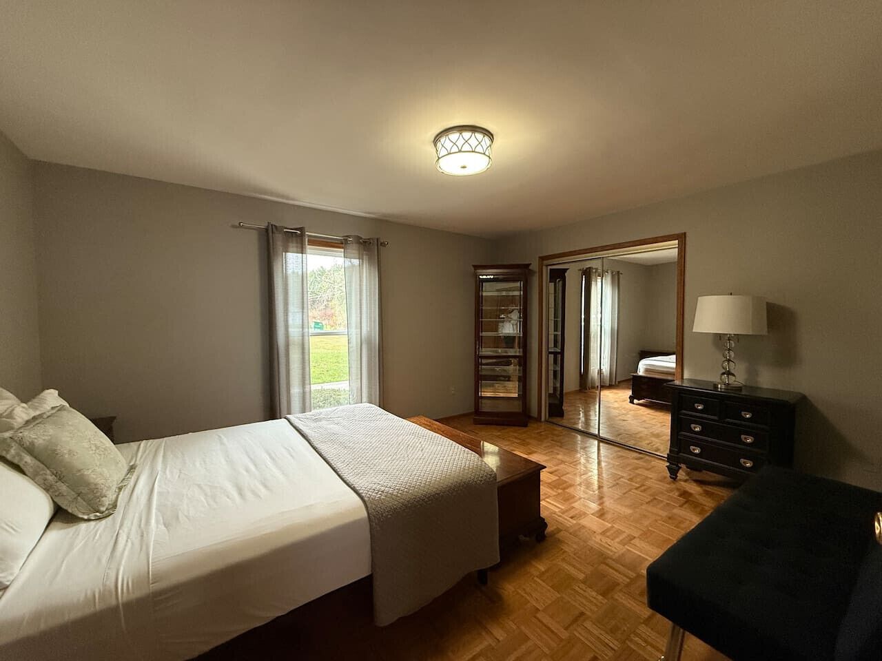 A bedroom with a bed, a dresser, a nightstand, and a mirror.