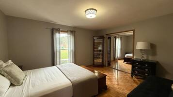 A bedroom with a bed, a dresser, a nightstand, and a mirror.