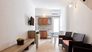 A modern kitchen with wooden cabinets, a dining area with wicker chairs, and a bench with a basket of flowers. - Corte Manzoni B&B (Melendugno)