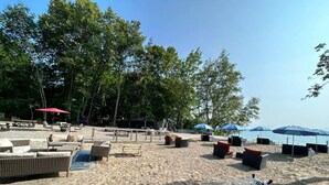 Un espace aménagé au bord de la plage, avec des sièges en plein air, des parasols et un hamac.