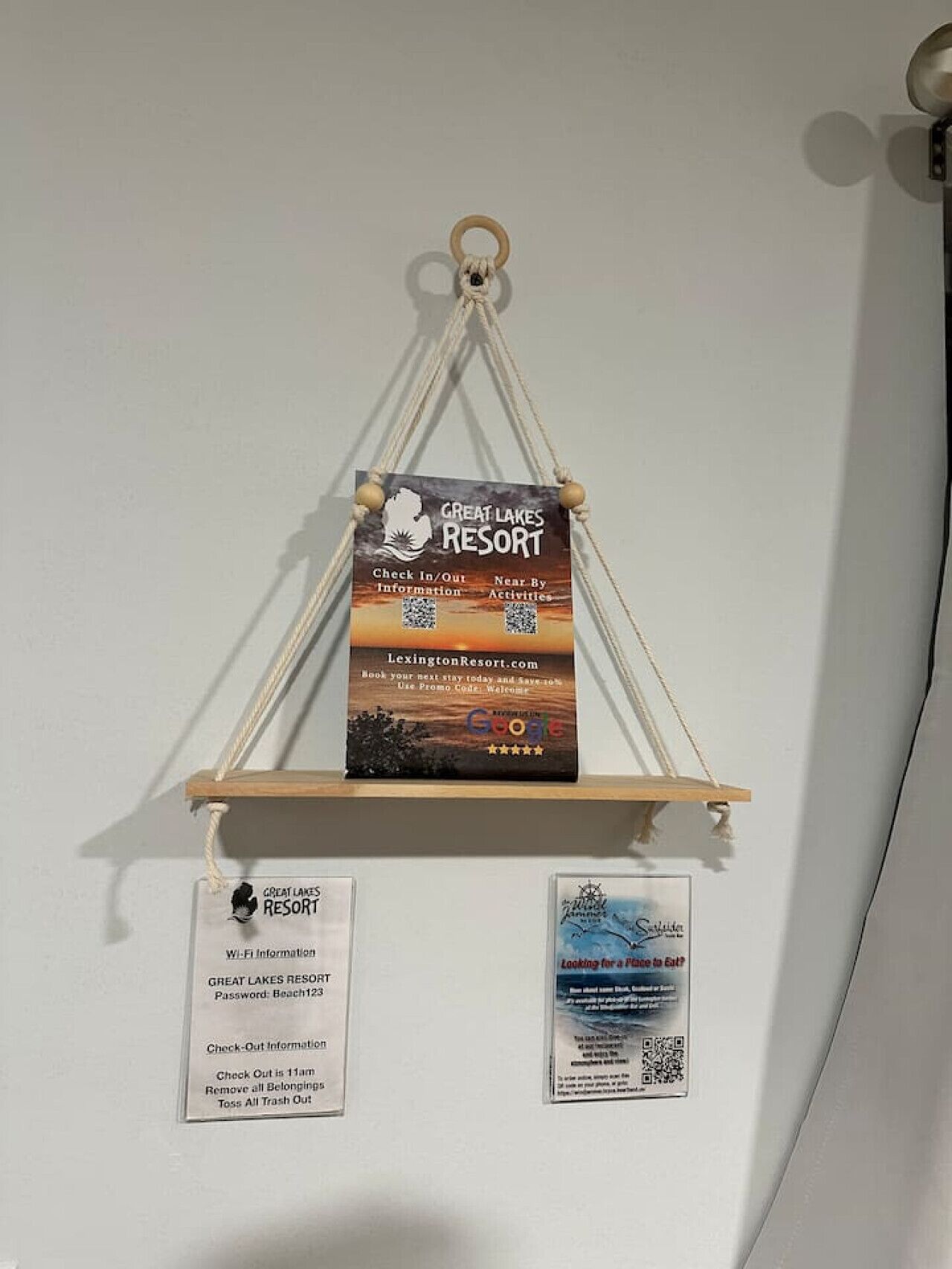 Un letrero montado en la pared para Great Lakes Resort con códigos QR para información de registro de entrada/salida y un código promocional.