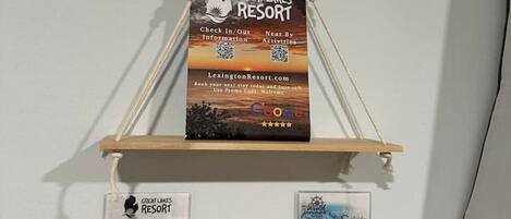 Un letrero montado en la pared para Great Lakes Resort con códigos QR para información de registro de entrada/salida y un código promocional.