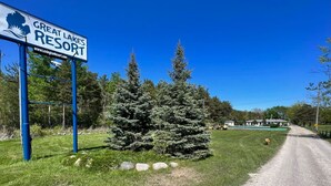 A sign for Great Lakes Resort with a clear view of the surrounding greenery and a gravel path leading to the property. - Great Lakes Resort - Jr Suite - Suite 7 (Lexington)
