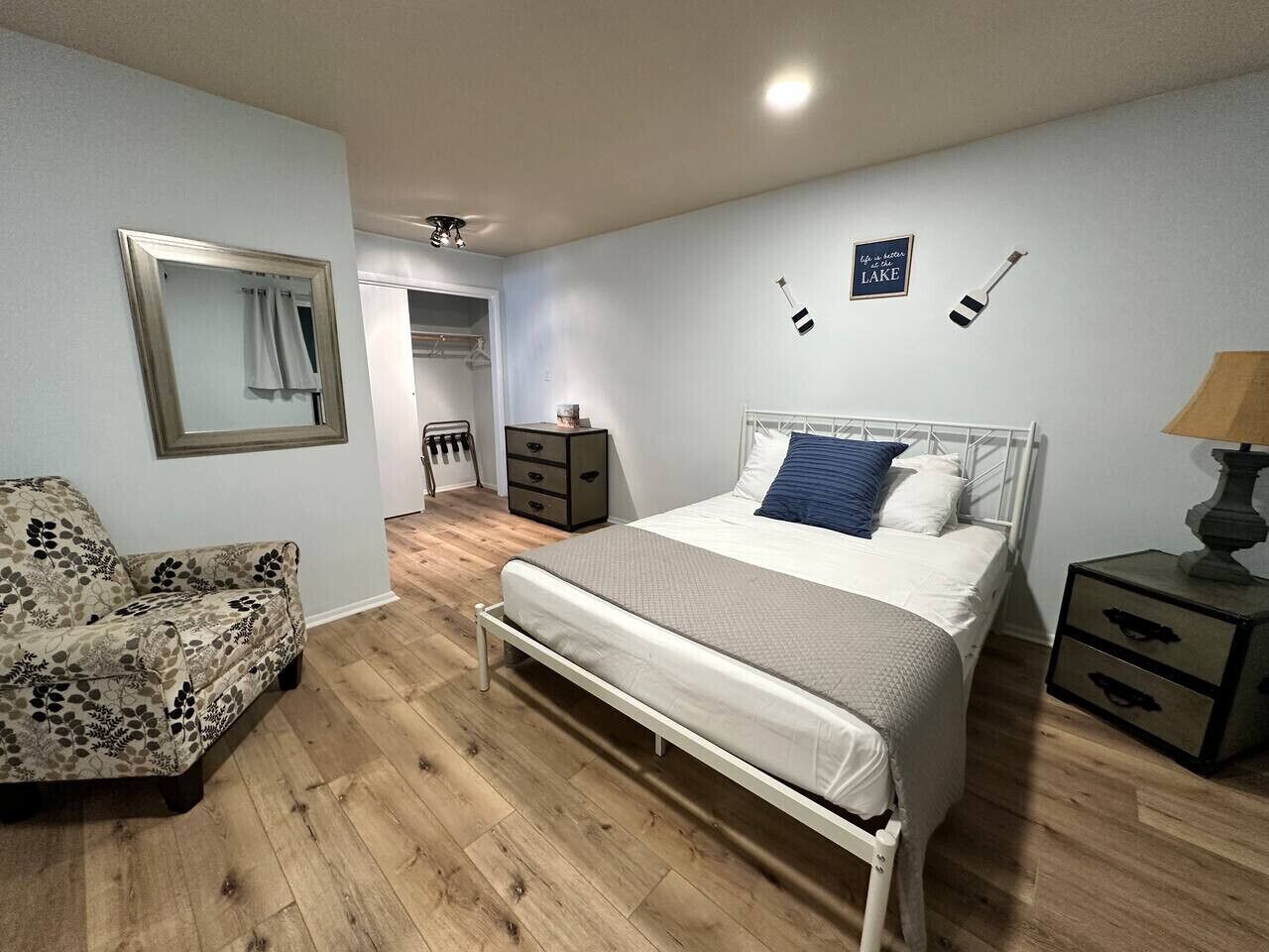 A bedroom with a bed, a chair, a dresser, and a nightstand.