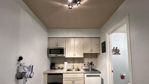 Une cuisine de taille réduite avec des meubles blancs, un four à micro-ondes, une cuisinière et un lave-vaisselle.