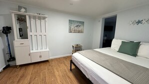 A bedroom with a bed, a white wardrobe, a small bedside table, and a painting on the wall. - Great Lakes Resort - Beach Studio - Suite 16 (Lexington)