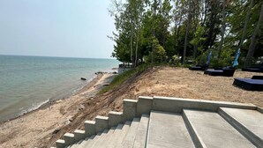 Concrete steps leading to a beach with a view of the sea and trees in the background. - Great Lakes Resort - Beach Studio - Suite 16 (Lexington)