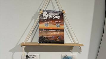 A wall-mounted sign for Great Lakes Resort with QR codes for check-in/out information and a promo code.