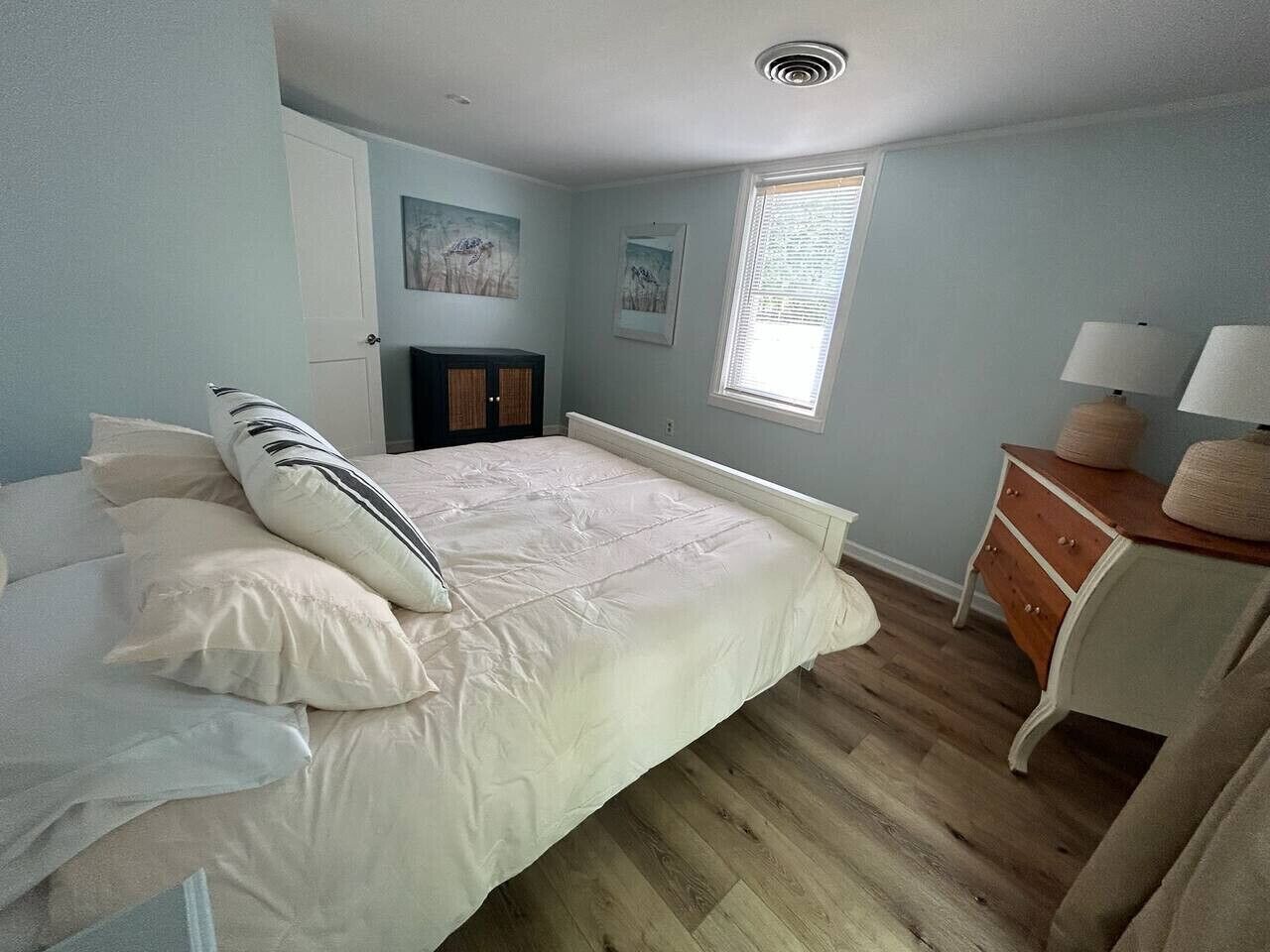 A bedroom with a bed, a dresser, a nightstand, and a window.