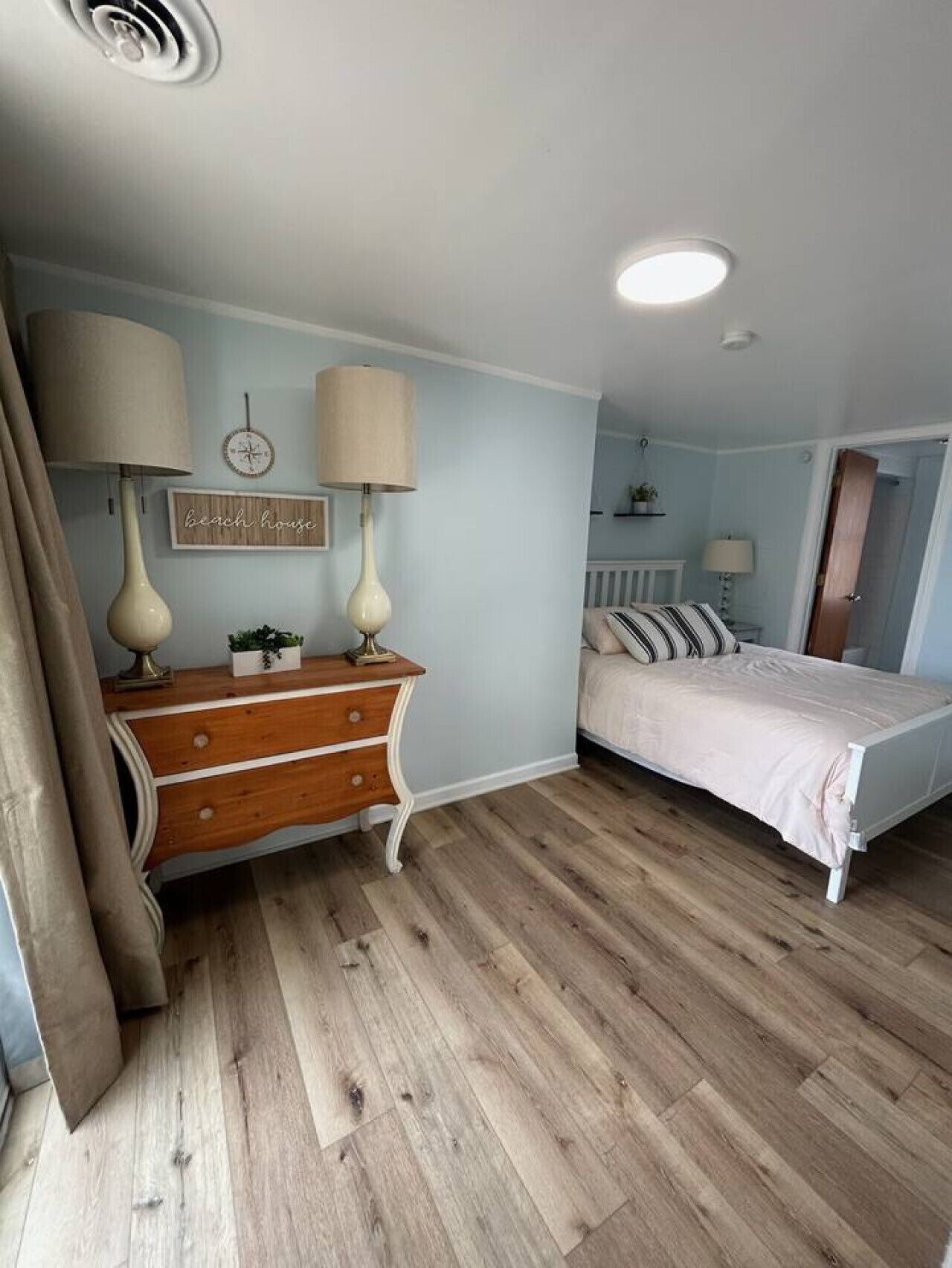 Un dormitorio con un aparador de madera, una cama con ropa de cama a rayas y un reloj de pared.