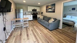 A compact living space with a kitchenette, a gray sofa, a dining table, and a bed. - Great Lakes Resort - Family Suite - Suite 2 (Lexington)
