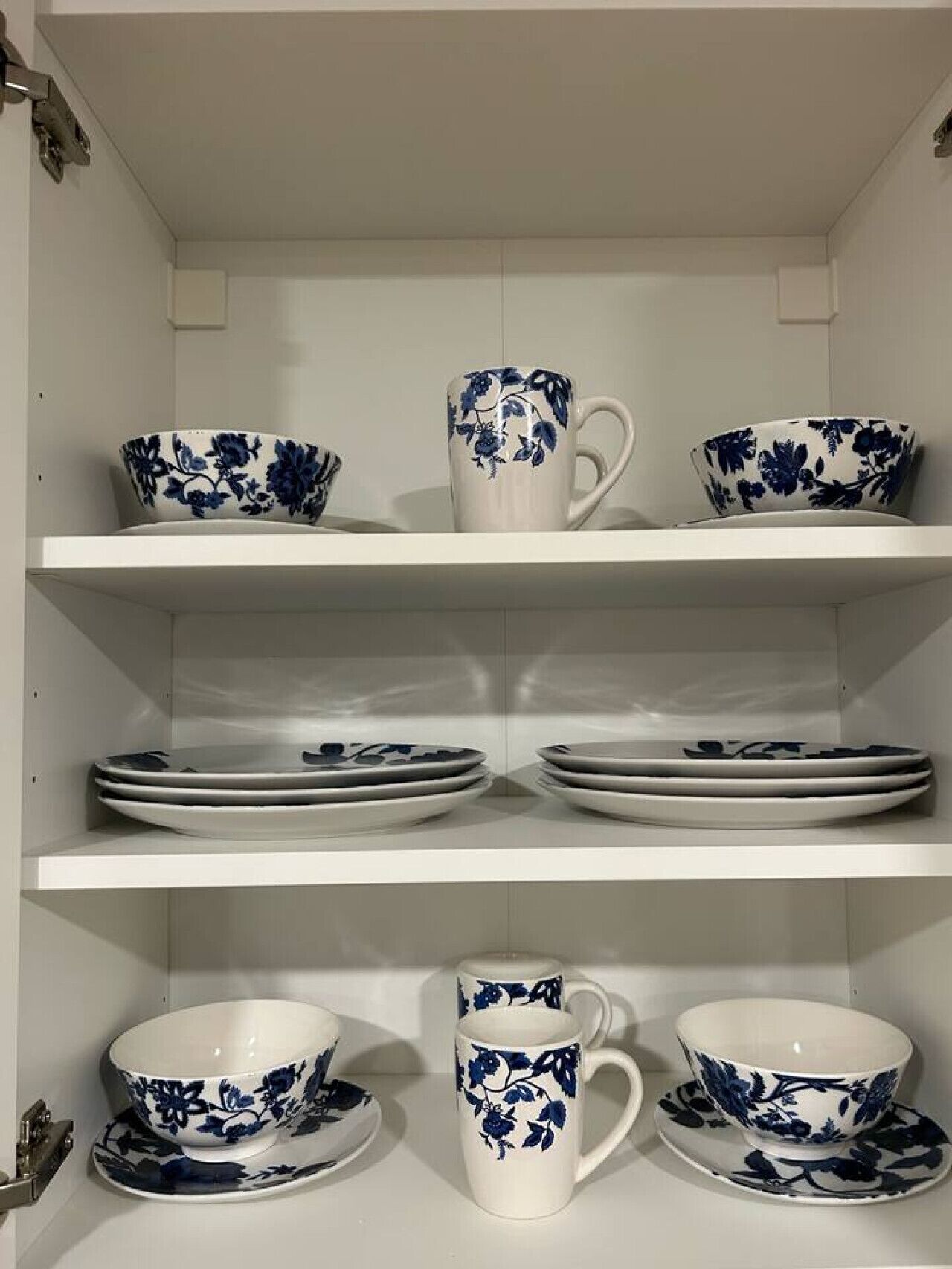 A kitchen with white shelves holding various white and blue ceramic dishes.