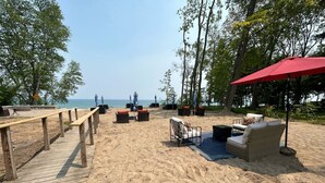 A beachside seating area with wooden deck, lounge chairs, and a red umbrella. - Great Lakes Resort - Family Suite - Suite 3 (Lexington)