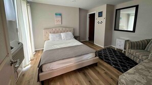 Une chambre avec un grand lit, un canapé, une petite table et un miroir.