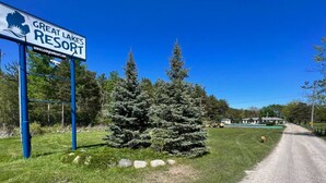 Une enseigne indiquant l’emplacement du complexe hôtelier Great Lakes Resort, avec un ciel dégagé et un chemin de gravier.