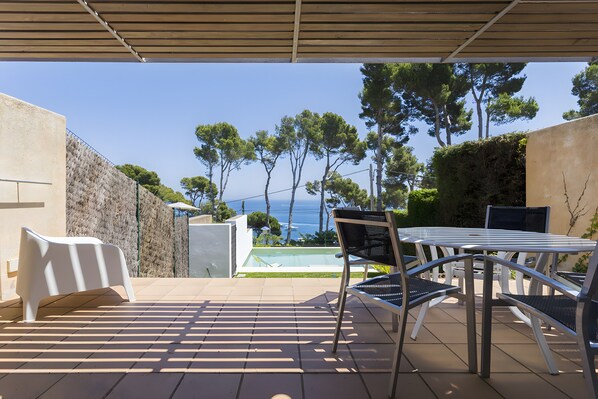 An outdoor patio with a table and chairs, a pool, and a view of the sea and trees. - Holiday Home 'Ona' with Balcony and Wi-Fi (Calella de Palafrugell)