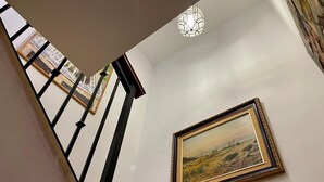 A staircase with a black railing, a framed painting on the wall, and a geometric light fixture on the ceiling. - Casa Rural Lomalinda: Mountain Views, Wi-Fi, and Air Conditioning (Granada)