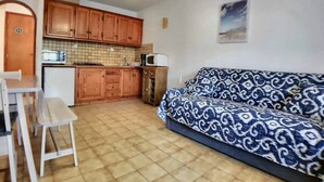 A compact living space with a kitchenette, a sofa, and a dining area. - Appa L'olivier 18 rue Louis Pasteur (Saintes-Maries-de-la-Mer)