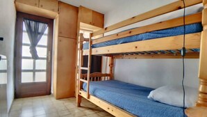 A bunk bed with a ladder, a small window with curtains, and a tiled floor. - Appa L'olivier 18 rue Louis Pasteur (Saintes-Maries-de-la-Mer)