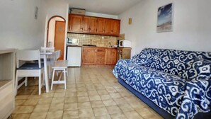 A compact living space with a kitchenette, a dining area, and a sofa. - Appa L'olivier 18 rue Louis Pasteur (Saintes-Maries-de-la-Mer)
