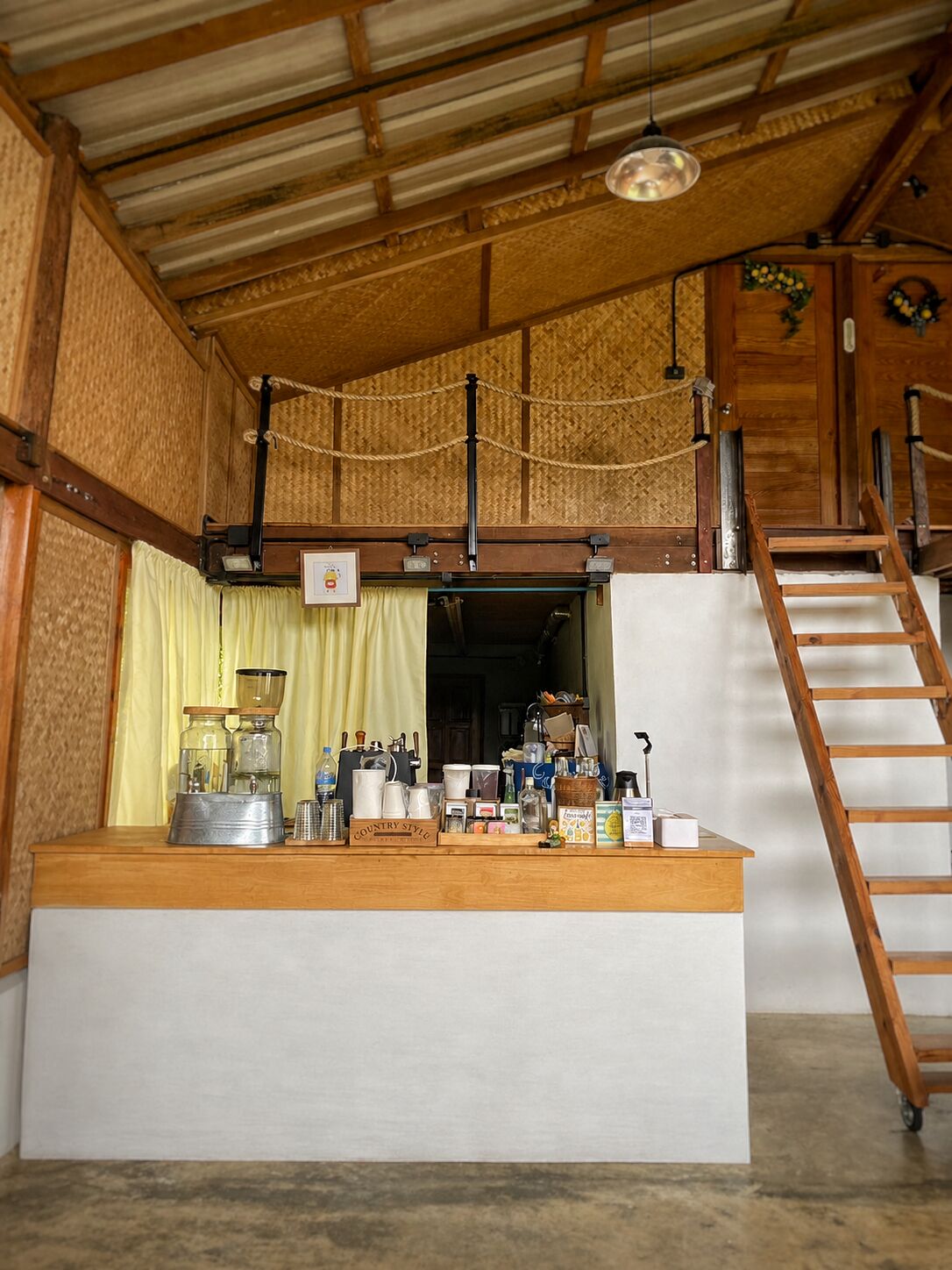Una cocina rústica con mostrador de madera, una cafetera y una escalera que conduce a una zona superior.